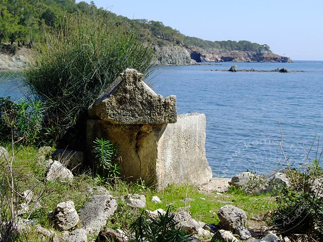 9-03-21-Phaselis-008-s.jpg - Steinsarkophage direkt am Strand, im Hintergrund die Klippen mit der Nordnekropole, im Meer die Reste des antiken Wellenbrechers